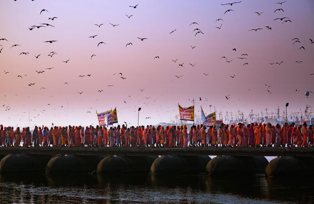 Akharas (ascetic orders) with their banners cross a pontoon bridge on their way to shahi snan (royal bath) during Basant Panchami at Prayag Kumbh, 2019. 